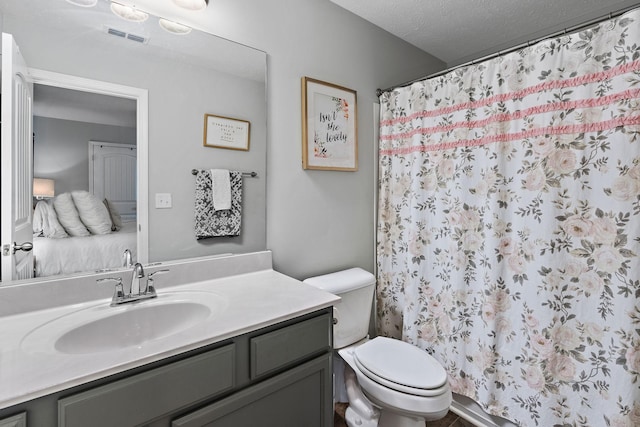 bathroom featuring a textured ceiling, curtained shower, toilet, and vanity