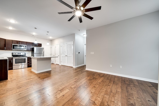 kitchen featuring dark brown cabinetry, appliances with stainless steel finishes, a kitchen island, decorative light fixtures, and light hardwood / wood-style floors