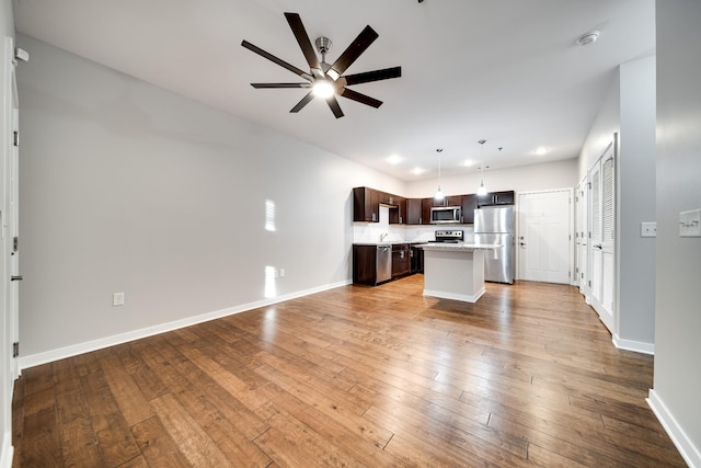 kitchen featuring stainless steel appliances, dark brown cabinets, hanging light fixtures, light hardwood / wood-style flooring, and a center island