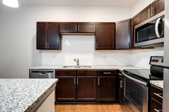 kitchen with light stone countertops, stainless steel appliances, decorative backsplash, and sink