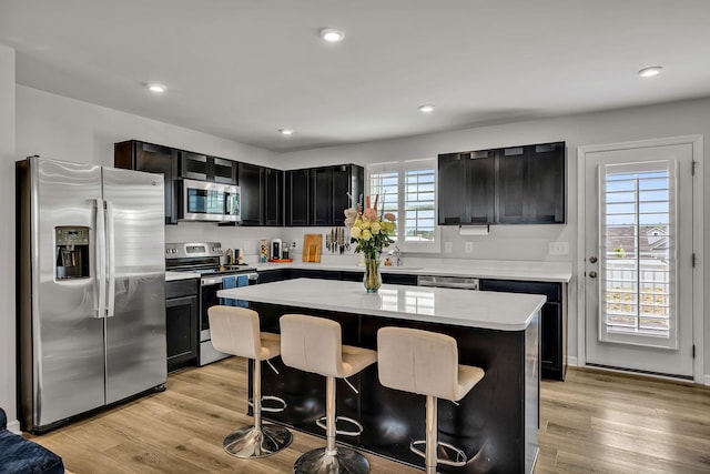 kitchen with a breakfast bar, a center island, stainless steel appliances, and a healthy amount of sunlight