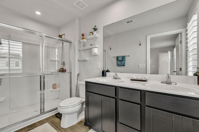 bathroom featuring hardwood / wood-style floors, toilet, a shower with door, and vanity