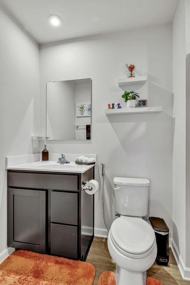 bathroom with toilet, vanity, and hardwood / wood-style floors