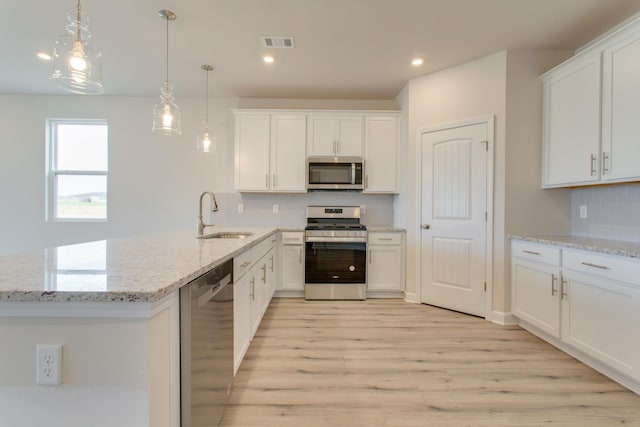 kitchen with stainless steel appliances, hanging light fixtures, sink, and white cabinets