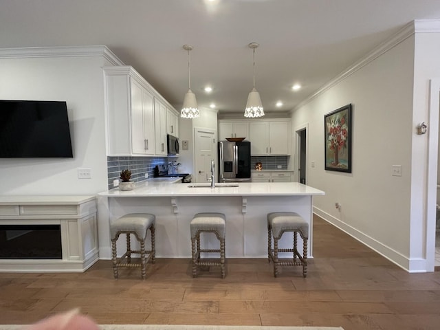 kitchen with kitchen peninsula, stainless steel appliances, white cabinets, and tasteful backsplash