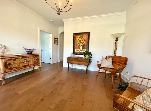 sitting room with crown molding, hardwood / wood-style floors, and a notable chandelier