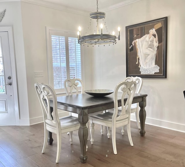 dining space featuring ornamental molding, wood-type flooring, and a notable chandelier