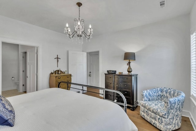 bedroom with ensuite bathroom and hardwood / wood-style floors