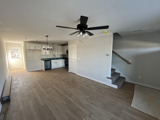 unfurnished living room with ceiling fan with notable chandelier and hardwood / wood-style floors