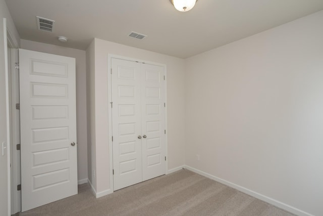 unfurnished bedroom with light carpet and a closet