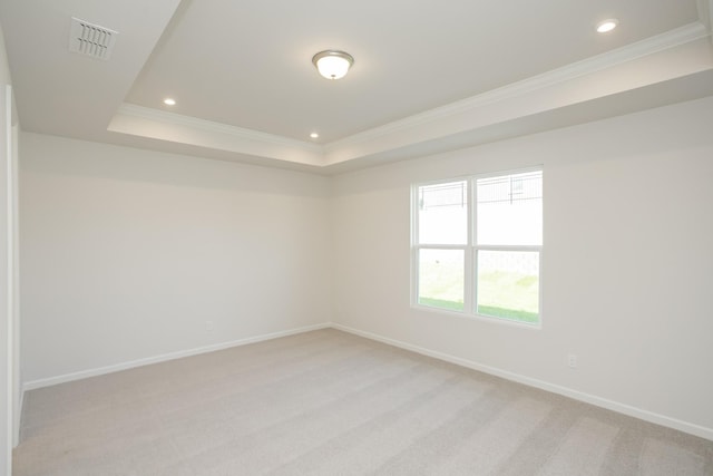 carpeted empty room featuring ornamental molding and a tray ceiling