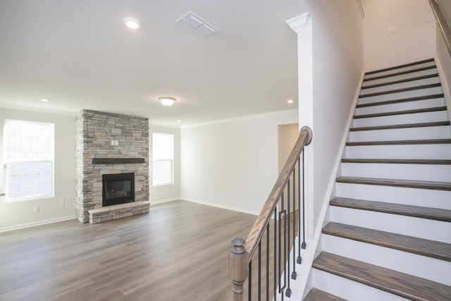 unfurnished living room with crown molding, a stone fireplace, and hardwood / wood-style flooring