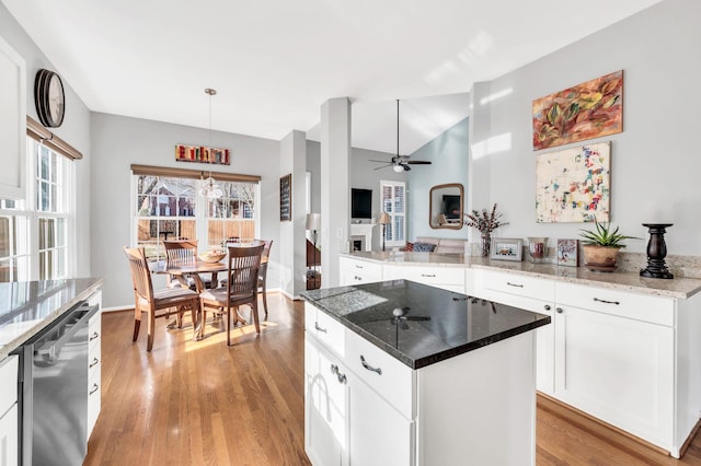 kitchen with white cabinetry, dark stone countertops, a kitchen island, pendant lighting, and stainless steel dishwasher