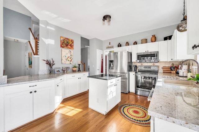 kitchen with white cabinets, kitchen peninsula, sink, and stainless steel appliances