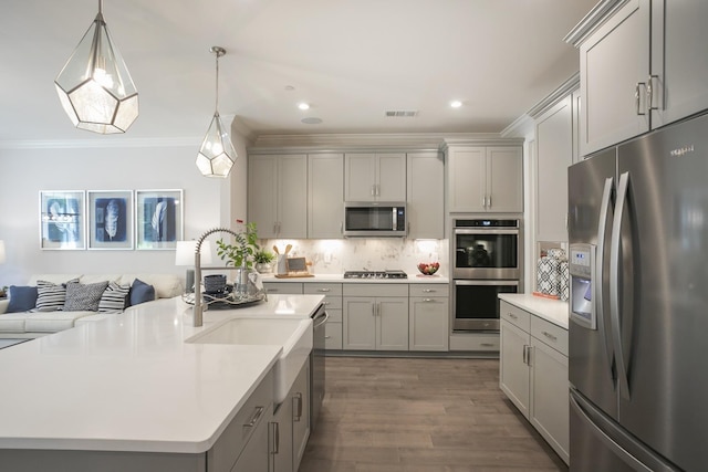 kitchen featuring appliances with stainless steel finishes, a kitchen island with sink, backsplash, and gray cabinets