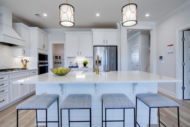 kitchen featuring premium range hood, hanging light fixtures, a center island with sink, and stainless steel appliances