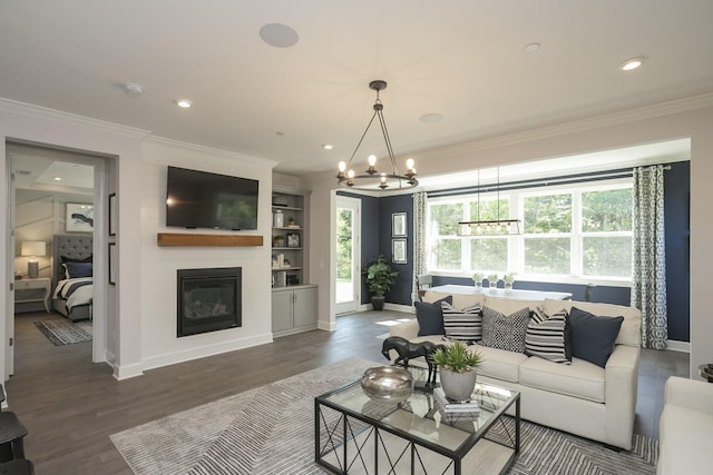 living room with an inviting chandelier, a large fireplace, dark hardwood / wood-style flooring, and crown molding