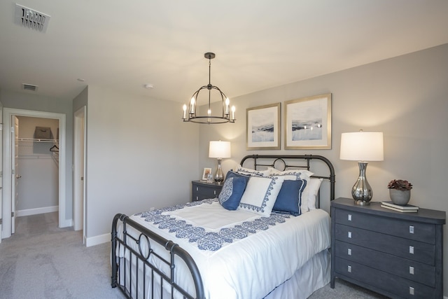 bedroom with a spacious closet, a closet, light colored carpet, and an inviting chandelier