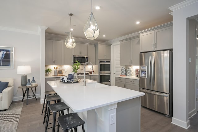 kitchen with stainless steel appliances, backsplash, gray cabinets, a large island, and a breakfast bar