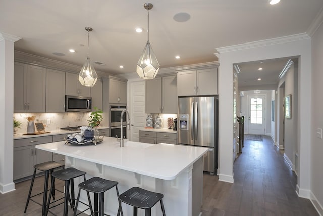 kitchen featuring appliances with stainless steel finishes, decorative backsplash, a kitchen breakfast bar, a large island, and gray cabinetry