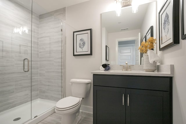 bathroom featuring toilet, vanity, and an enclosed shower