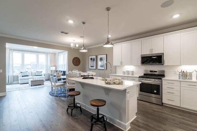 kitchen featuring an island with sink, appliances with stainless steel finishes, pendant lighting, white cabinets, and sink