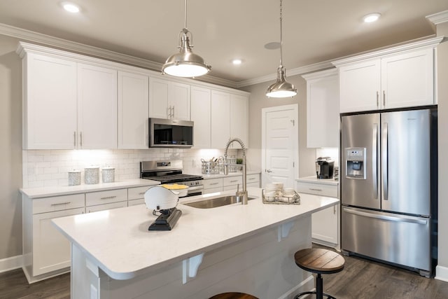 kitchen featuring a center island with sink, pendant lighting, sink, stainless steel appliances, and white cabinets