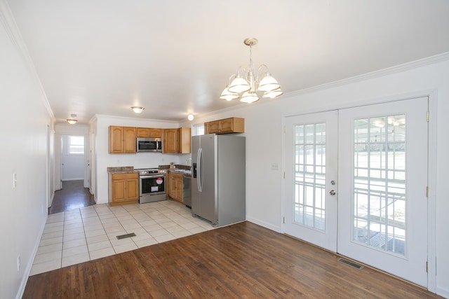 kitchen with french doors, hanging light fixtures, stainless steel appliances, crown molding, and light hardwood / wood-style flooring