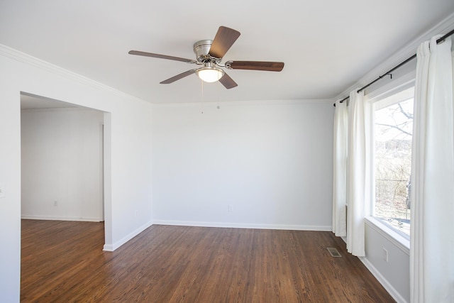 empty room with crown molding, dark wood-type flooring, a wealth of natural light, and ceiling fan