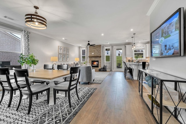 dining area featuring ornamental molding, a fireplace, and hardwood / wood-style flooring