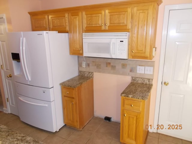 kitchen with light tile patterned floors, decorative backsplash, light stone counters, and white appliances