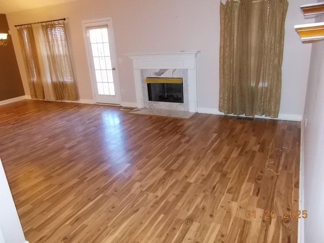 unfurnished living room featuring a high end fireplace and wood-type flooring