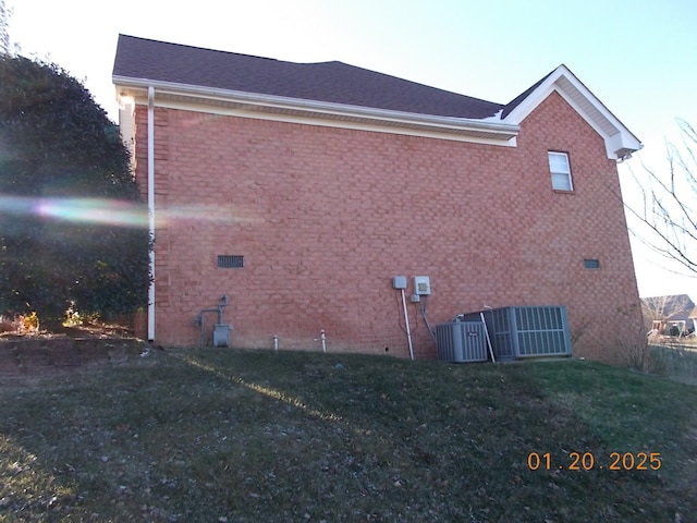 view of side of home with cooling unit and a lawn