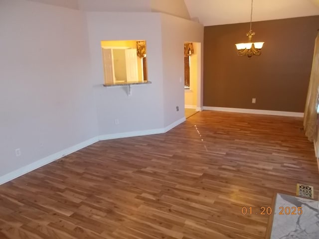 spare room with vaulted ceiling, wood-type flooring, and a notable chandelier