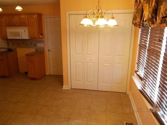 unfurnished dining area featuring an inviting chandelier and light tile patterned floors