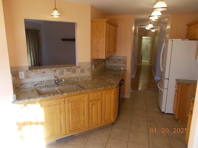 kitchen featuring tasteful backsplash, white fridge, pendant lighting, sink, and light tile patterned floors