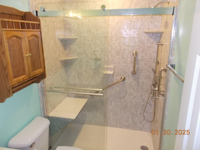 bathroom featuring toilet and a shower with door