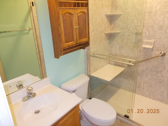 bathroom featuring a shower with door, toilet, and vanity