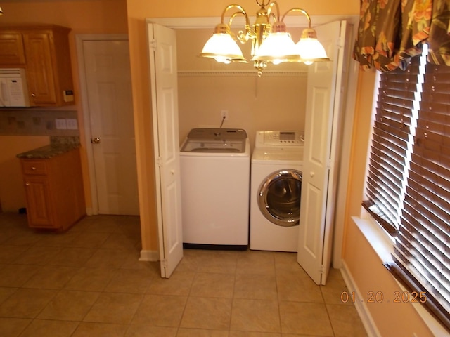 laundry area with light tile patterned floors, an inviting chandelier, and washing machine and clothes dryer