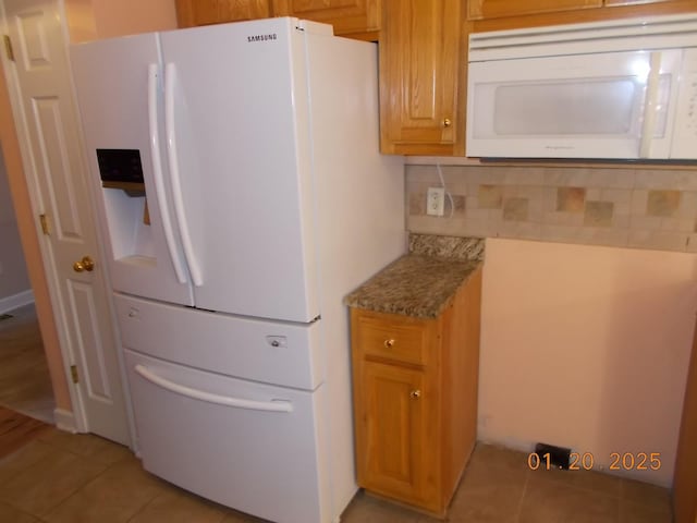 kitchen with tasteful backsplash, light stone counters, light tile patterned flooring, and white appliances