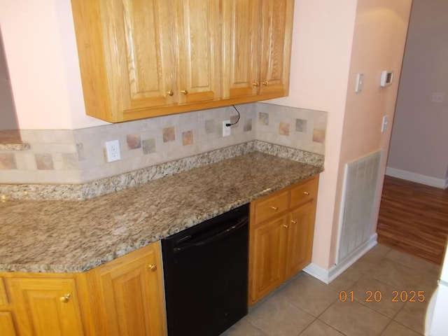 kitchen featuring light stone countertops, backsplash, light tile patterned floors, and dishwasher