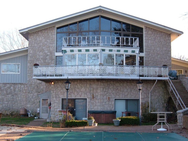 back of property featuring a balcony and a hot tub