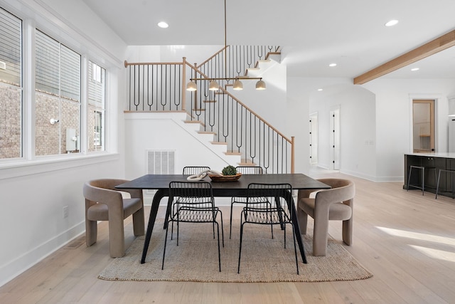 dining space with beamed ceiling and light hardwood / wood-style floors