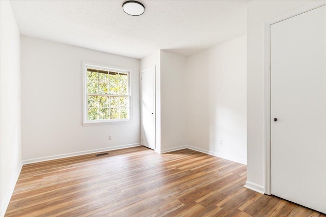 spare room featuring a textured ceiling and light hardwood / wood-style floors