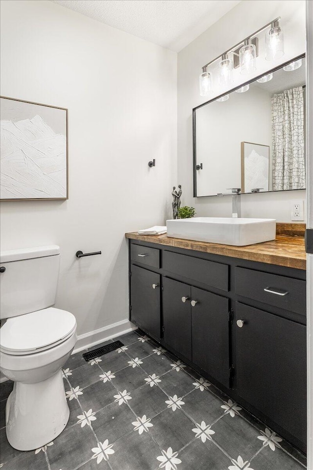 bathroom featuring vanity, toilet, and a textured ceiling