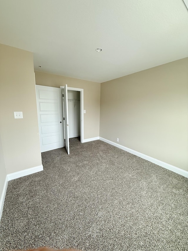 unfurnished bedroom with dark carpet and a closet