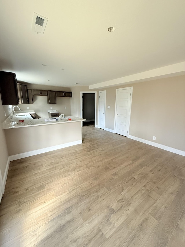 unfurnished living room featuring sink and light hardwood / wood-style flooring