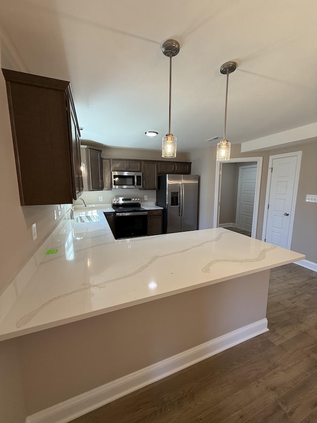 kitchen featuring dark wood-style floors, dark brown cabinetry, appliances with stainless steel finishes, a peninsula, and hanging light fixtures