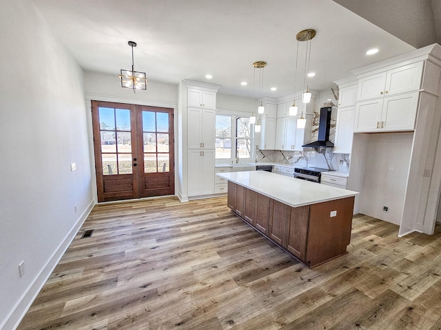 kitchen with white cabinetry, wall chimney exhaust hood, decorative light fixtures, and a center island