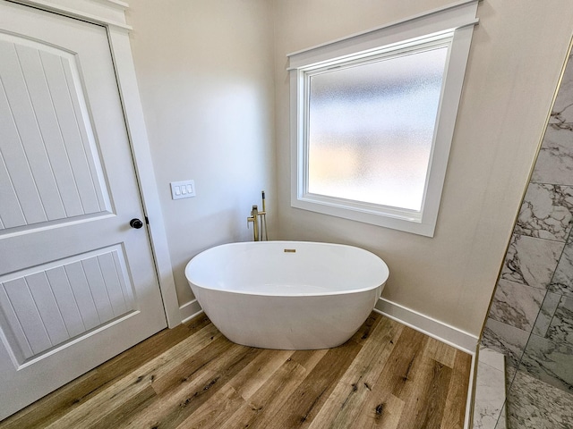 bathroom with a bath and hardwood / wood-style floors